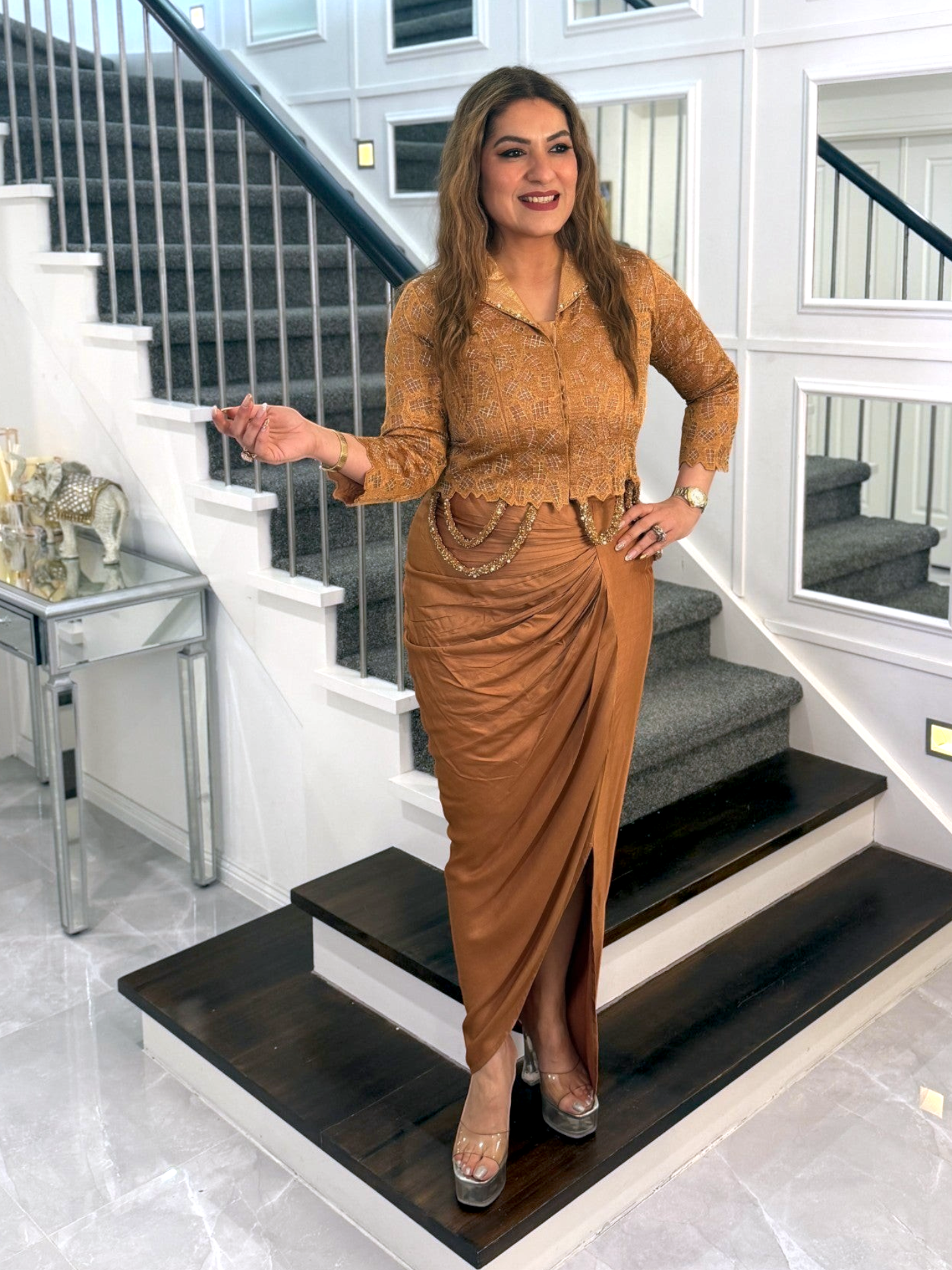 Woman wearing a PanacheByDivya gold Indo-western outfit with a textured collared top and draped skirt on a staircase.